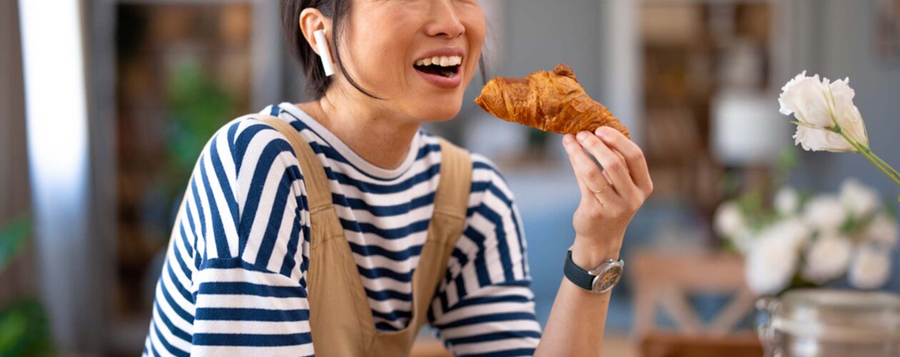 a woman eating a croissant for breakfast