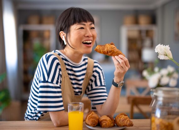 a woman eating a croissant for breakfast