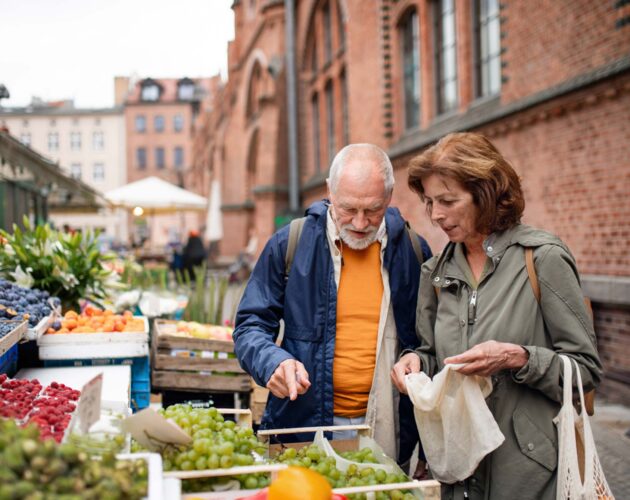 an older couple browsing fruit in an open market
