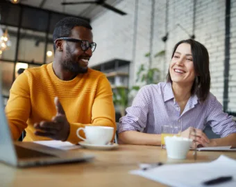 Man and woman sitting in office drinking coffee