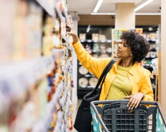 woman reaching for food in grocery store center aisle