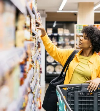 woman reaching for food in grocery store center aisle