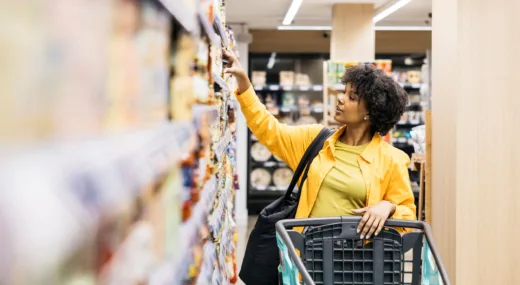 woman reaching for food in grocery store center aisle