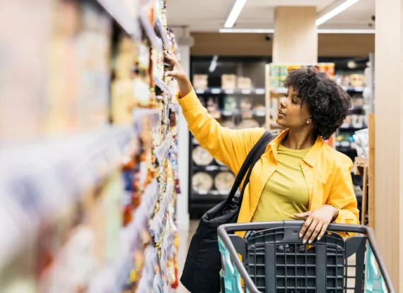 woman reaching for food in grocery store center aisle